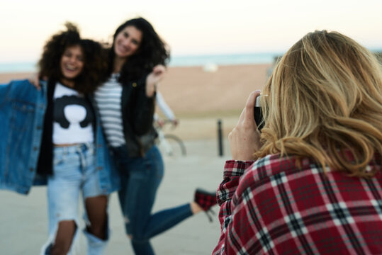 Blonde girl taking photo of smiling girlfriends.