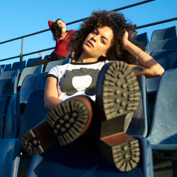 Portrait of beautiful girl on grandstand seat with her shoes in close-up.