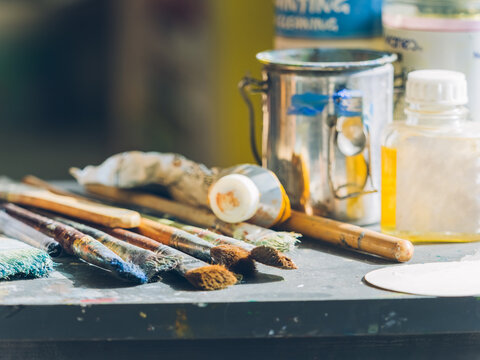 closeup of paintbrushes and some containers on desk