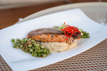 Grilled salmon with green peas, mashed potato in white plate on dining table