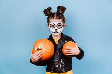 Happy Halloween concept. Zombie little girl holds two pumpkin, wears creative makeup, has fun...