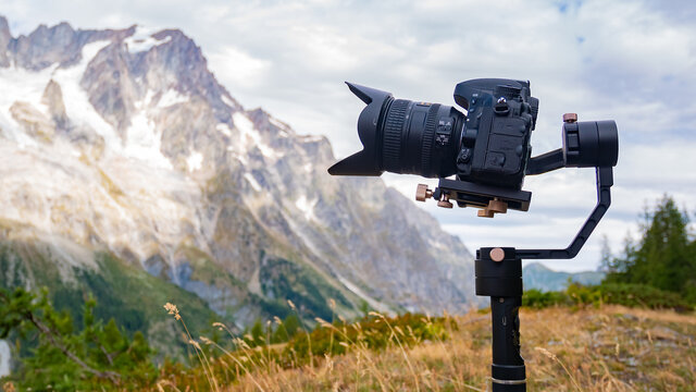 Camera on a gimbal filming. Mountains and clouds on the background.