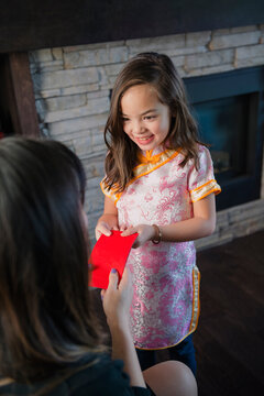Mother Handing Red Envelope to Daughter Chinese New Year