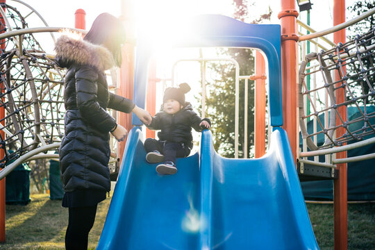 Adorable toddler boy playing on slide