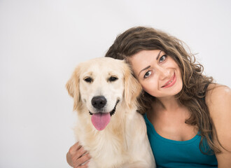 Closeup woman smilling and looking at camera with her dog isolated on white. Portrait of curly young woman and golden retriever closeup isolated on white background. Beautiful woman stroking her dog.