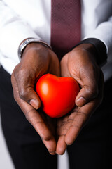 Close-up. Hands of an African American male doctor cardiologist with a red heart. Health care