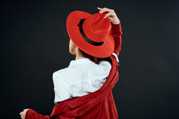 Woman in red hat jacket white shirt back view dark background