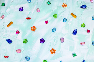 Trendy plastic colorful crystal rhinestone for sewing on green abstract background. Diy clothing decoration concept, copy space