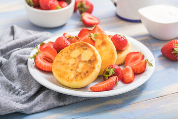 Sweet Cottage cheese pancakes on plate served strawberries. Russian syrniki, ricotta fritters or curd fritters.