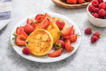 Sweet Cottage cheese pancakes on plate served strawberries. Russian syrniki, ricotta fritters or curd fritters.