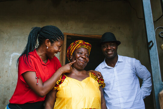 Mother smiles as her children fuss over her and prod her to make her smile.