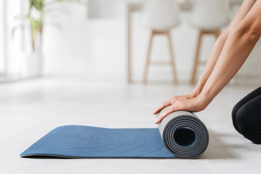 Close up of woman hands prepairing fitness mat for yoga or workout classes at home on a floor. Time for meditation, fitness sessions, virtual online yoga, wellbeing and wellness concepts