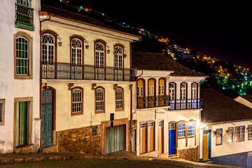 Obraz premium Facades of houses in colonial architecture on an old cobblestone street in the city of Ouro Preto illuminated at night