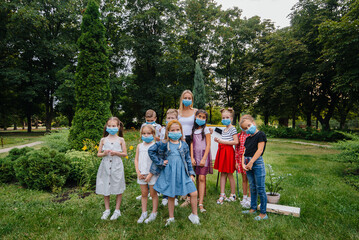Obraz premium A class of masked school children is engaged in outdoor training during the epidemic. Back to school, learning during the pandemic