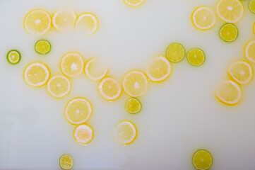 Turbid soapy water in the bath with slices of lemon and lime top view in full frame. Citrus. Spa with milk in the bath for rejuvenation.