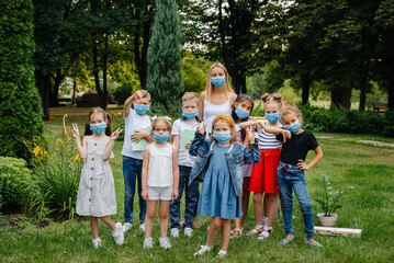 Fototapeta premium A class of masked school children is engaged in outdoor training during the epidemic. Back to school, learning during the pandemic