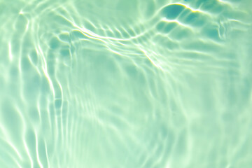 de-focused. Closeup of mint green transparent clear calm water surface texture with splashes and bubbles. Trendy abstract summer nature background. Mint colored waves in sunlight. Copy space.