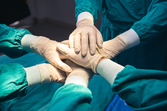 Cooperation of people in the medical community with hand together between surgeon doctor in the green suit to charity comment provide the most effective treatment to patients at Operating room.