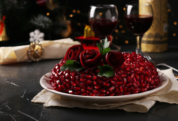 Traditional Russian Salad Pomegranate bracelet decorated roses of beetroot on dark background. New Year's festive salad, Closeup