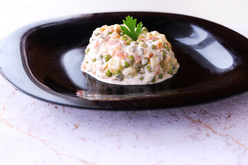 Traditional salad with cooked vegetables with mayonnaise. black marble background. close up view.