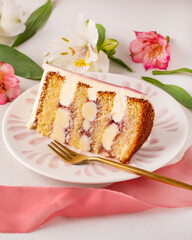 White layered cake slice, jam, and flowers.
