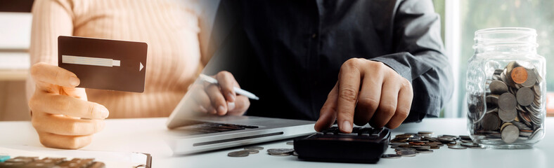 Business people use tablets and hold credit cards as an online shopping concept With a calculator and a book placed on the table
