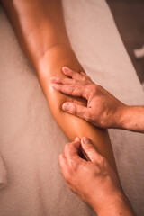 Detail of a physiotherapist's massage of the back of the right leg of a young woman lying on the table. Physio, ostiopathy, relaxing massage, motion video of treatment on the back