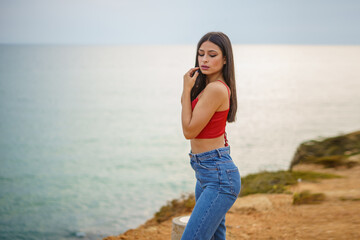 Chica caminando por ruta de playa camino de madera y vegetacion junto a un acantilado en cadiz el...