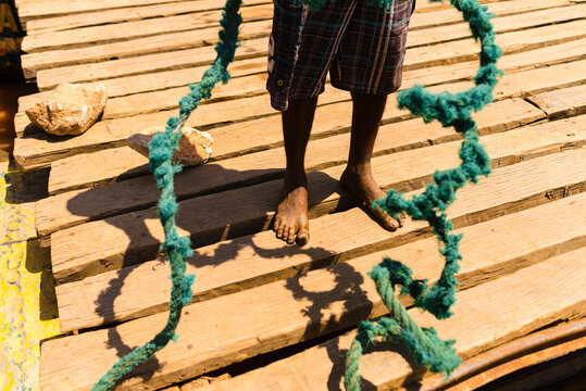 Unrecognizable low section of colored boatman with ropes. Travel, Madagascar, Ship, River, Boat