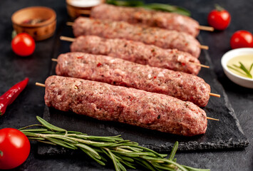 raw Lula kebab  on skewers with spices on a stone background 