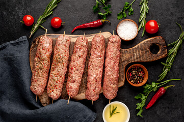 raw Lula kebab  on skewers with spices on a stone background 