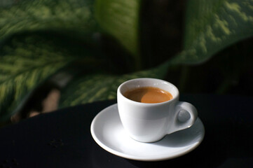 Espresso coffee in a white mug on the black table