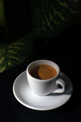 Espresso coffee in a white mug on the black table