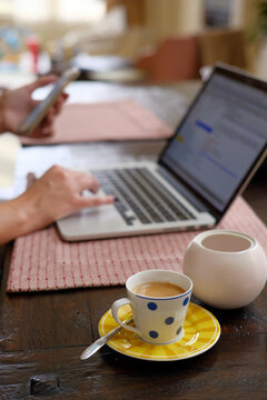 Woman using laptop computer with espresso.
