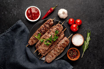 Grilled Lula kebab on skewers with spices in a black plate on a stone background