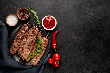 Grilled Lula kebab on skewers with spices in a black plate on a stone background with copy space