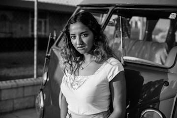 Chica posando junto a furgoneta vintage con puesta de sol de fondo de moda joven