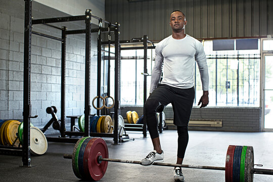 Black athlete standing at barbell in gym