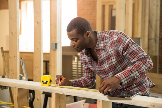 Worker measuring wood at construction site