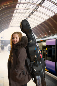 Musician carrying cello case in train station