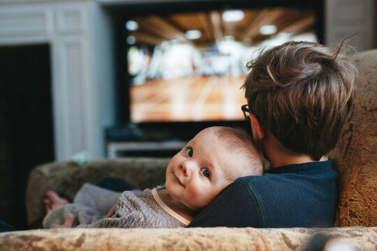 baby looking back at camera while being held by big brother
