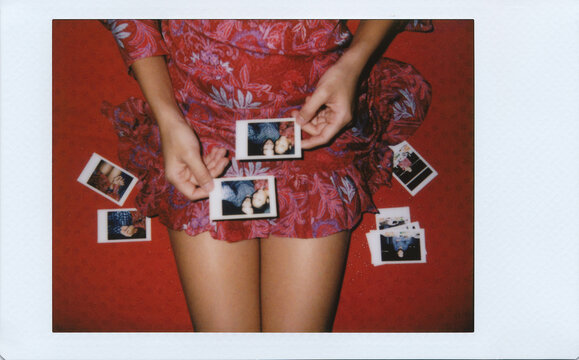 Woman in retro red paisley dress holding Polaroid photos