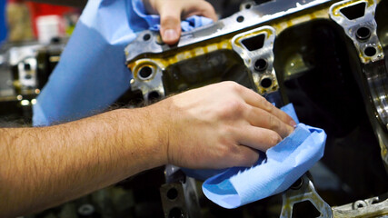 Close up video of male hand wipes the engine spare before installing into the motor. Footage. Auto mechanic working on car engine in mechanics garage.