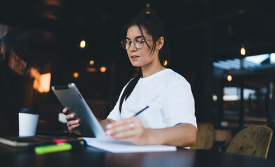 Concentrated young woman working on tablet in cafe