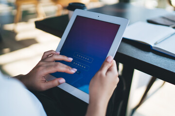 Cropped image of woman's hand taping on modern touchpad entering password for unlocking, female millennial using digital tablet sign in application