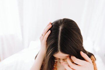 Young brunette woman showing her scalp, hair roots, color, brunette hair, hair loss or dry scalp problem.