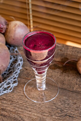 Red beet juice in a glass on a wooden table