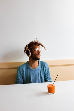 The guy in blue is feeling things, sitting on a bar with headphones on