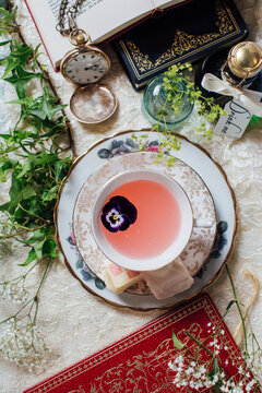 Overhead view of a pansy floating in a china cup of pink lemonade on a pretty party table