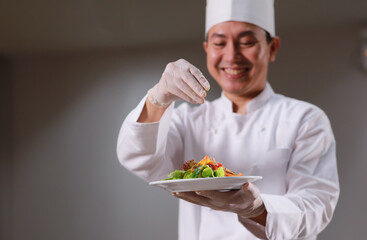 Close up portrait chef drop salt and papper topping on Salad